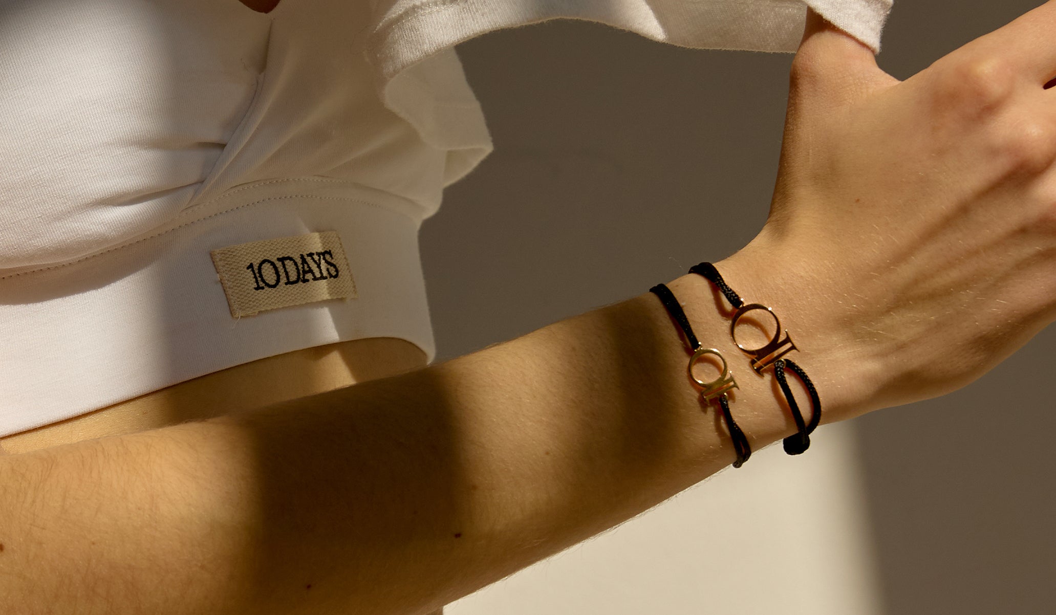 Close-up of woman wearing a white sporty bra and 2 10DAYS x The Finds braclets