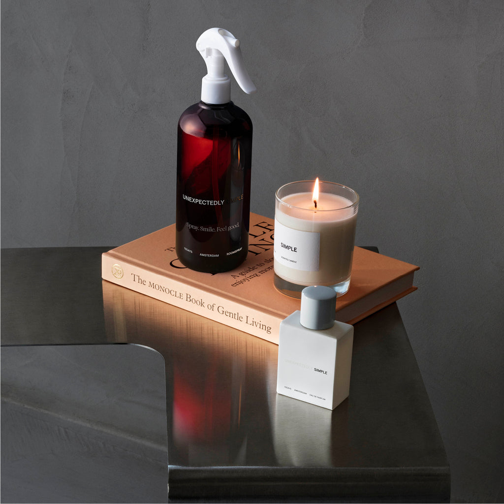 Table with a book and 3 products from the 10DAYS fragrances collection: a room spray, candle and perfume.