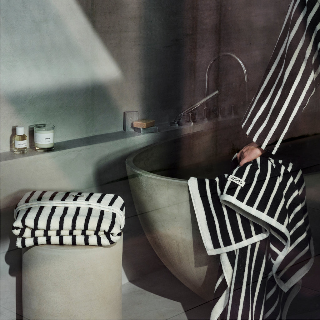 Bathroom showcasing black and white striped 10DAYS towels and 10DAYS fragrances.